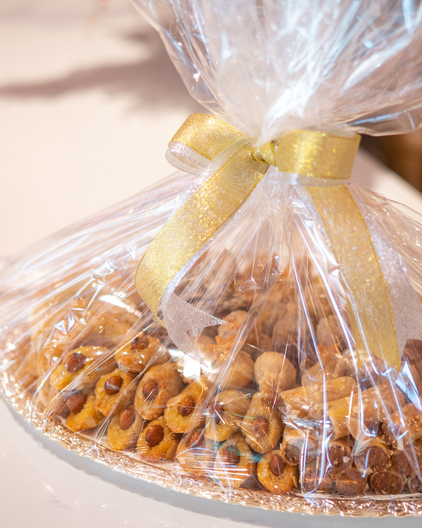 A tray of sweets wrapped in cellophane with a gold bow on the café counter