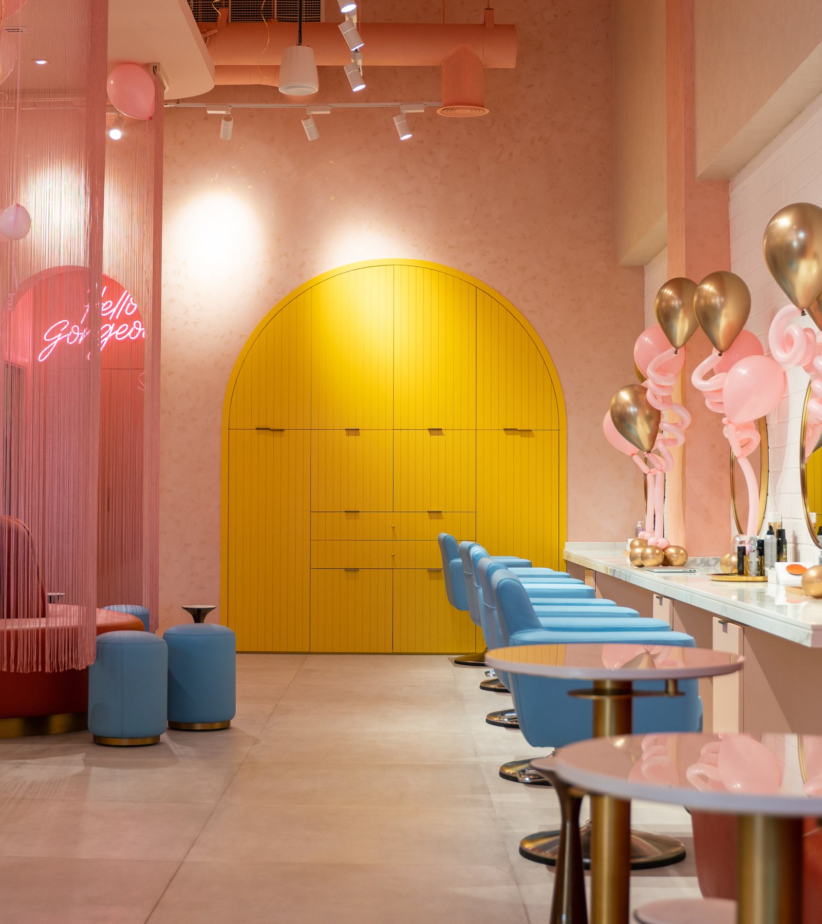 Inside Bellacure Al Seef Village Mall: the yellow arched doors, the Hello Gorgeous neon and blue stools along the nail bar