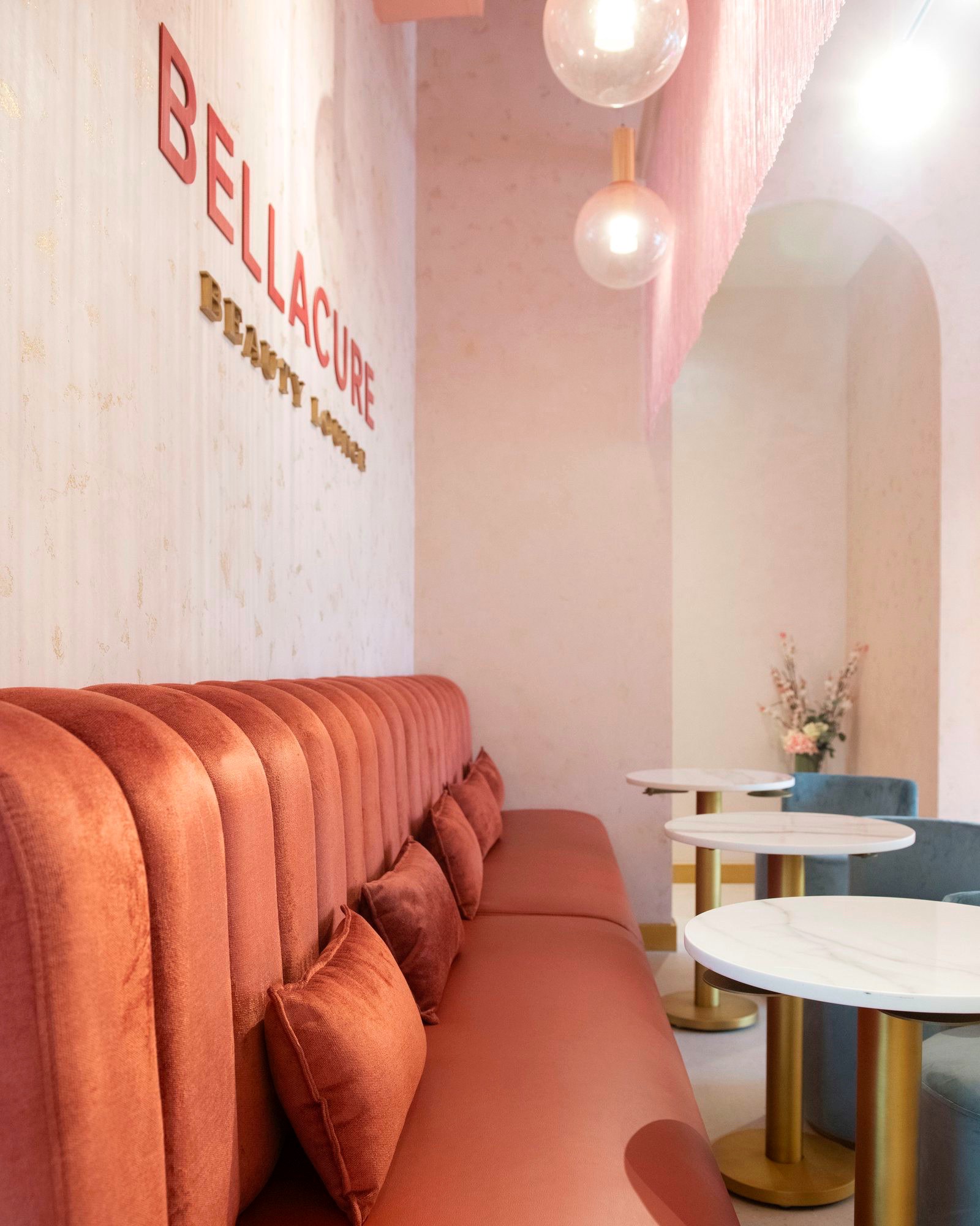 The Bellacure Beauty Lounge sign above the blush velvet banquette and marble tables at Sheikha Fatima Park