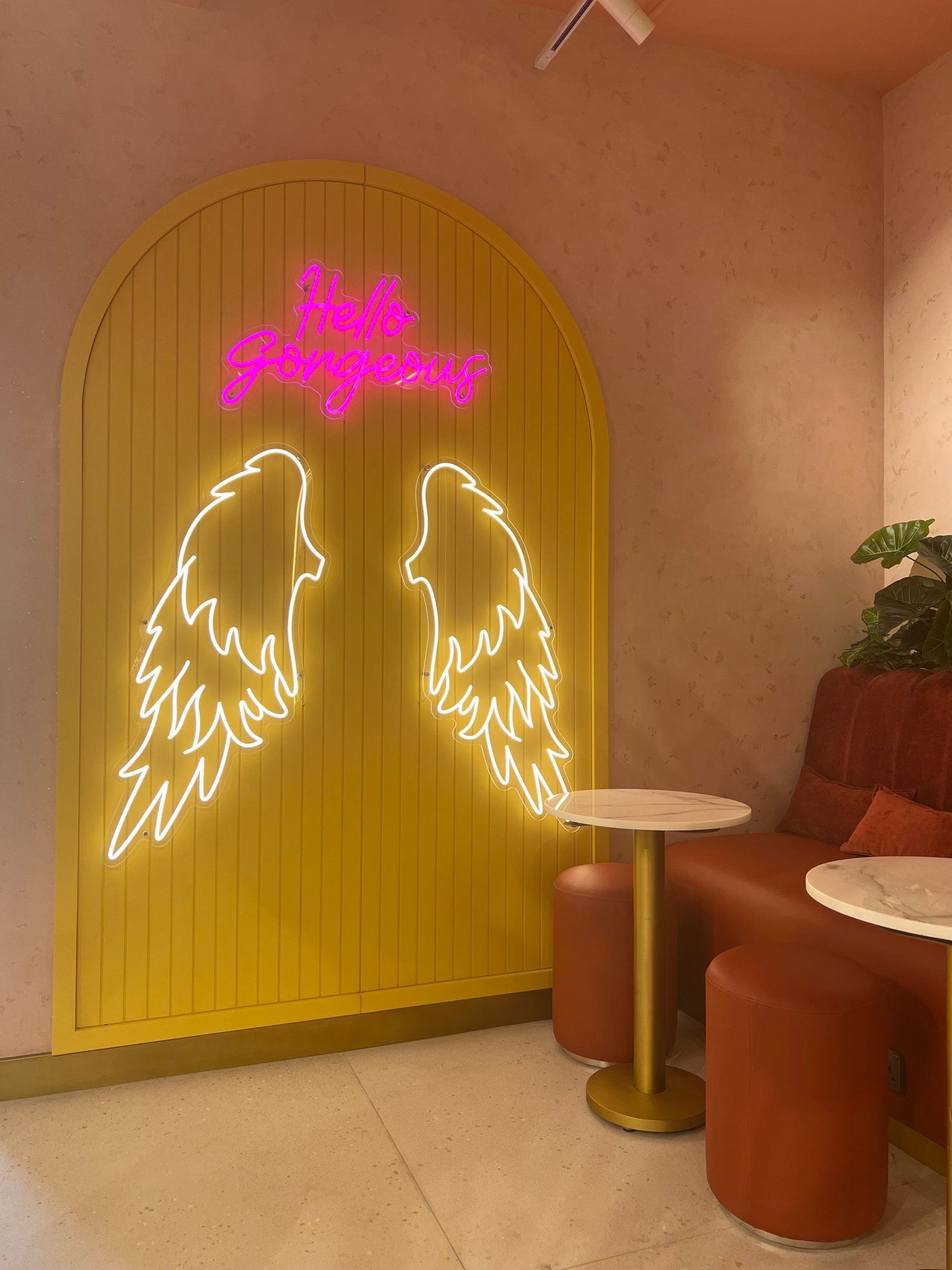 The Hello Gorgeous neon and wings on the yellow arch inside Bellacure Al Mamoura
