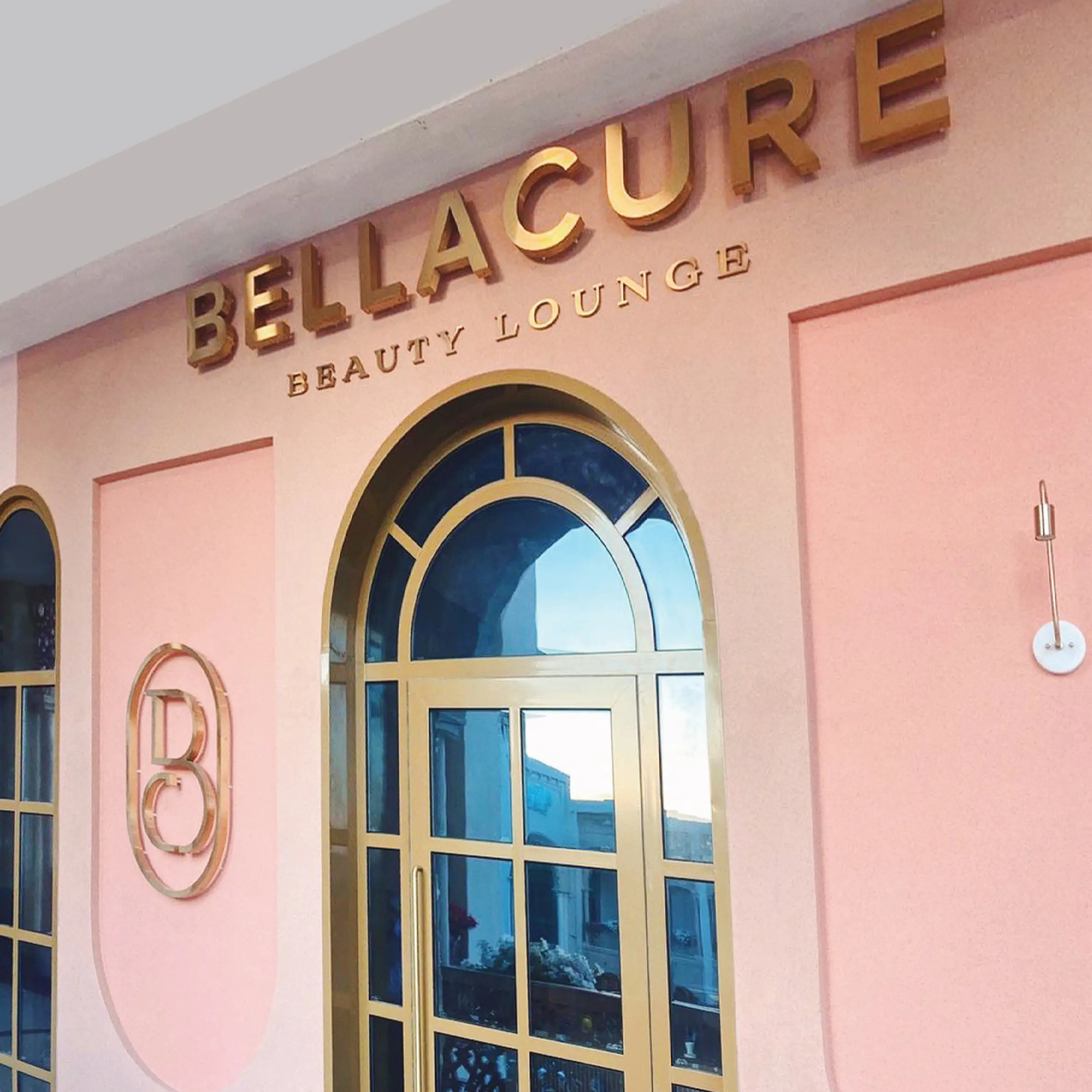 The pink Bellacure shopfront at Al Seef Village Mall, with gold lettering and an arched door